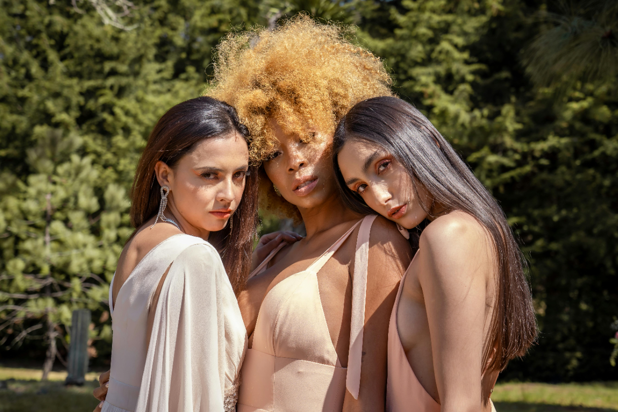 Three women posing for a picture in front of trees.